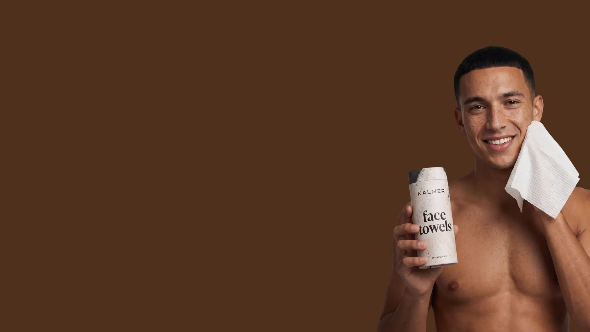 Man holding a KALMER face towels roll and patting his face dry with a fresh single-use towel