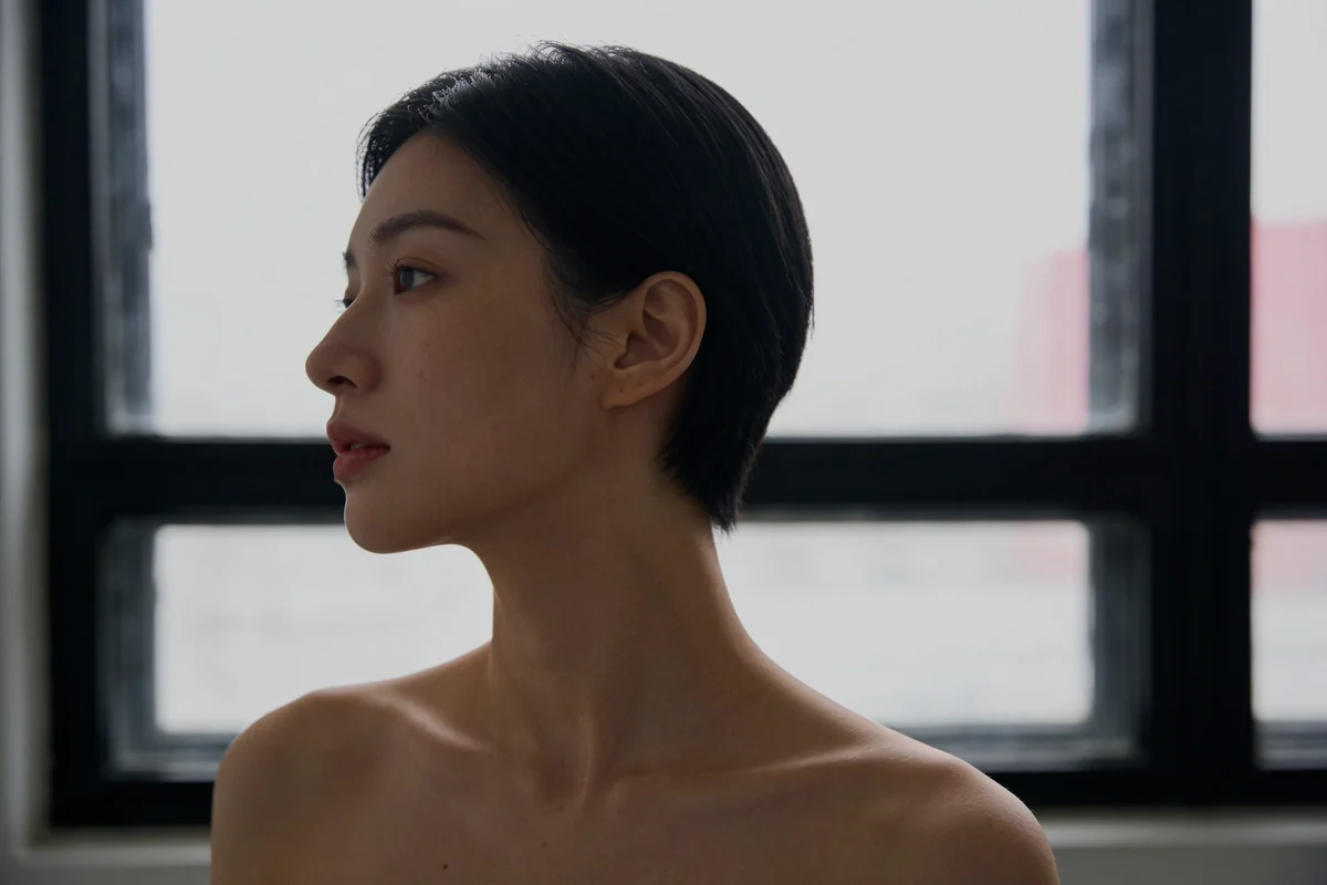 A woman's side profile against a window in natural light
