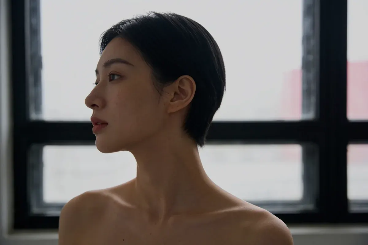 A woman's side profile against a window in natural light